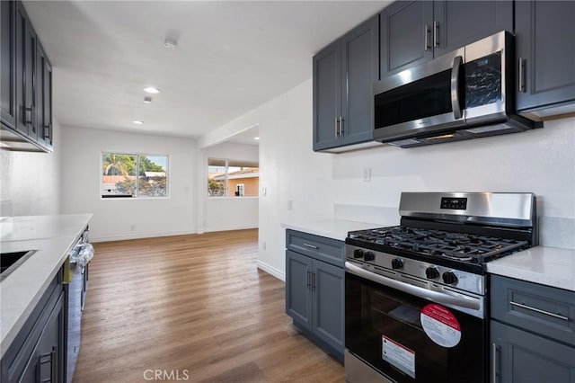 kitchen featuring appliances with stainless steel finishes, light wood-type flooring, and light stone counters