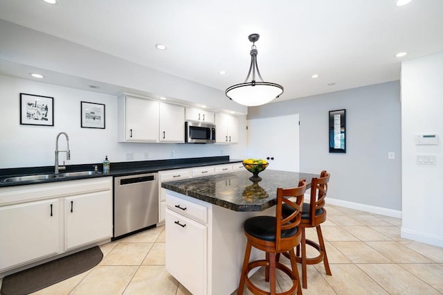 kitchen featuring pendant lighting, sink, white cabinetry, a kitchen island, and appliances with stainless steel finishes