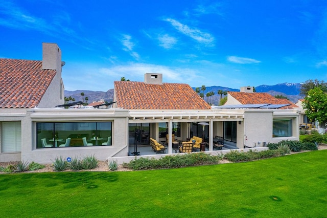 rear view of property with a mountain view, a yard, and a patio