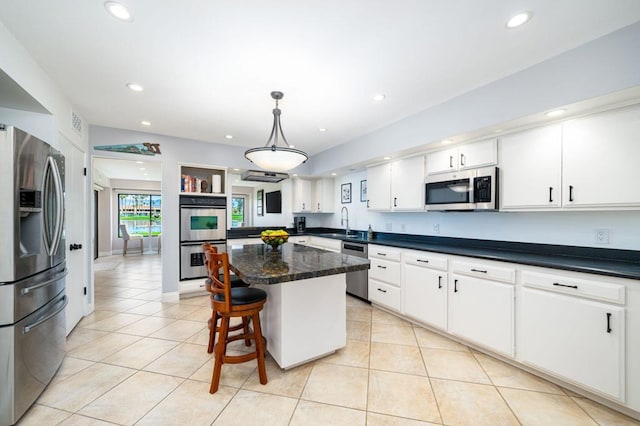 kitchen with appliances with stainless steel finishes, hanging light fixtures, white cabinetry, a center island, and sink