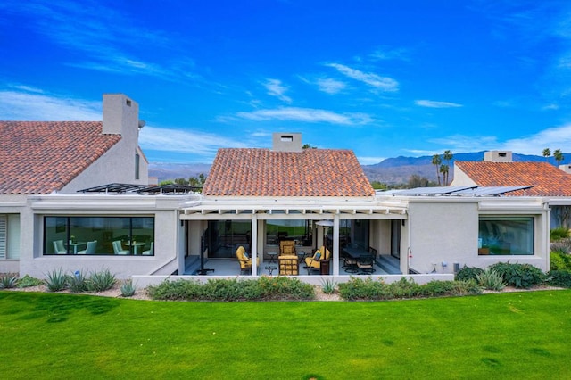 rear view of property with a lawn, a patio, and a mountain view