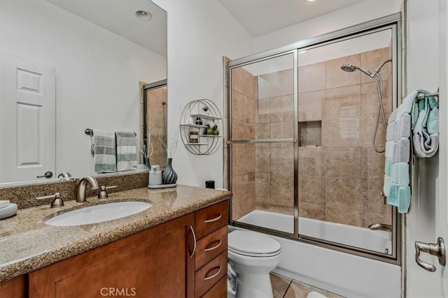 full bathroom with tile patterned flooring, vanity, toilet, and bath / shower combo with glass door