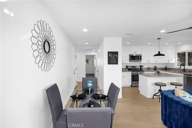 dining area featuring light wood-type flooring and sink