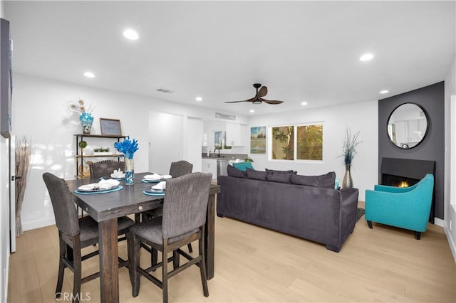 dining space with ceiling fan and light wood-type flooring