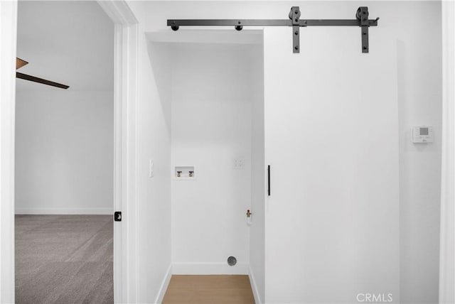 laundry area with light carpet, hookup for a washing machine, and a barn door