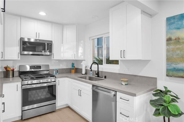 kitchen featuring white cabinets, sink, appliances with stainless steel finishes, and light hardwood / wood-style flooring