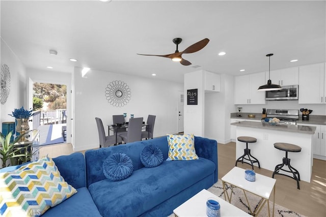 living room with light hardwood / wood-style floors and ceiling fan