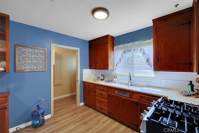 kitchen with backsplash, sink, range with gas cooktop, and light hardwood / wood-style floors