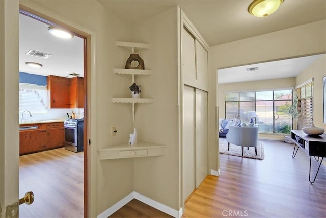 hall with light wood-type flooring and sink