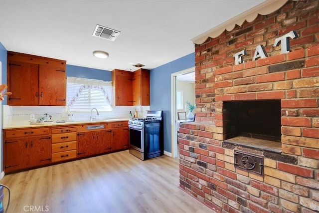 kitchen with stainless steel range with gas stovetop, sink, and light wood-type flooring