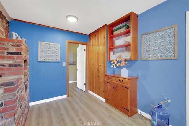 corridor with ornamental molding and light hardwood / wood-style flooring