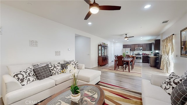 living room featuring light wood-type flooring and ceiling fan