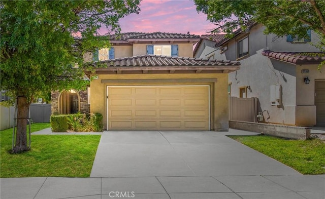 mediterranean / spanish-style home with a yard and a garage