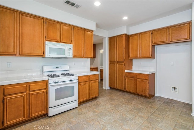 35375 Trevino Trl, Beaumont, CA 92223 - kitchen featuring white appliances, brown cabinetry, recessed lighting, tile counters, and baseboards