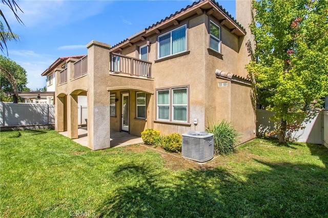 rear view of house with central air condition unit, a patio area, a balcony, and a yard