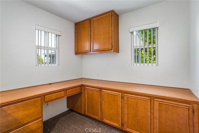 unfurnished office with built in desk and dark colored carpet