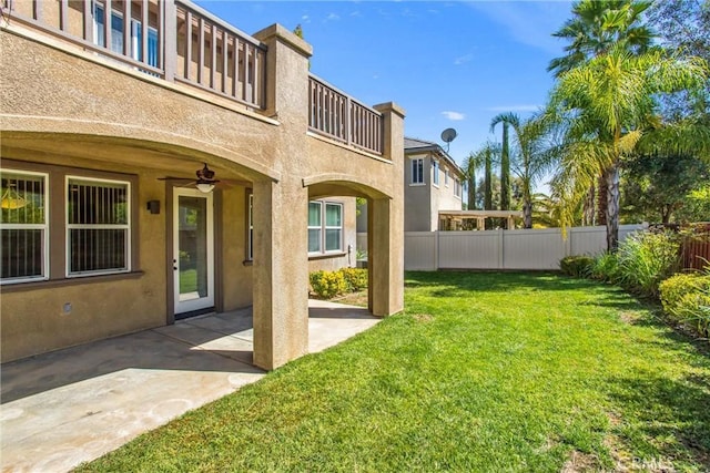 view of yard featuring a patio area, ceiling fan, and a balcony