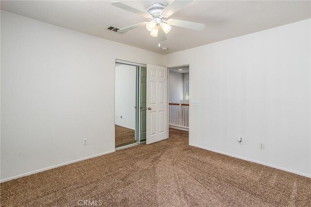 unfurnished bedroom with carpet, a closet, and ceiling fan