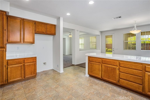 kitchen with tile countertops, decorative light fixtures, ceiling fan, and light colored carpet