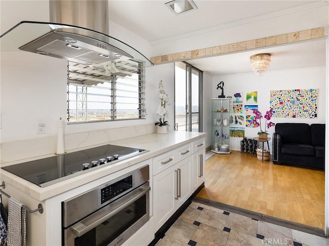 kitchen with ventilation hood, oven, black electric cooktop, light hardwood / wood-style floors, and white cabinetry