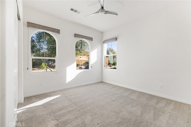 spare room with ceiling fan, light colored carpet, and a wealth of natural light