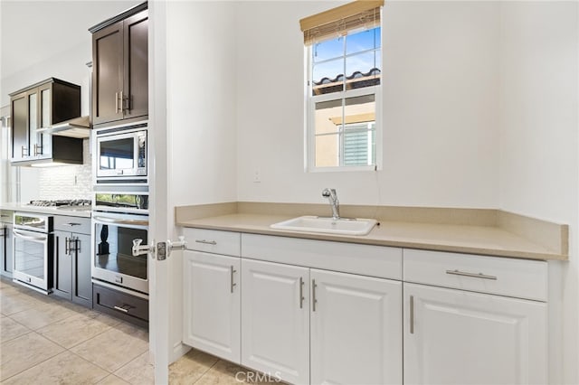 kitchen with white cabinets, light tile patterned flooring, sink, tasteful backsplash, and appliances with stainless steel finishes