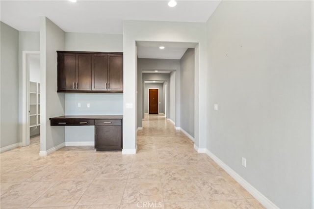 kitchen with dark brown cabinetry and built in desk