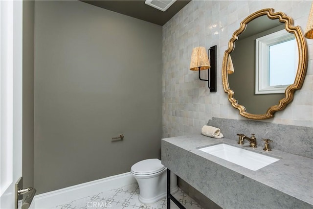 bathroom featuring tile walls, sink, and toilet