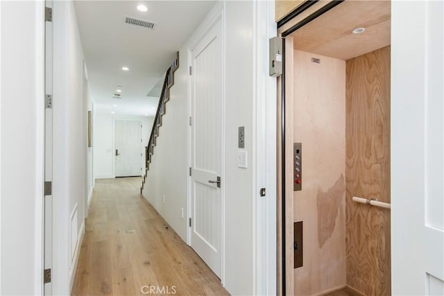 hallway featuring elevator and light hardwood / wood-style flooring