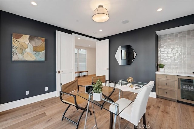 dining space featuring bar, wine cooler, and light hardwood / wood-style flooring