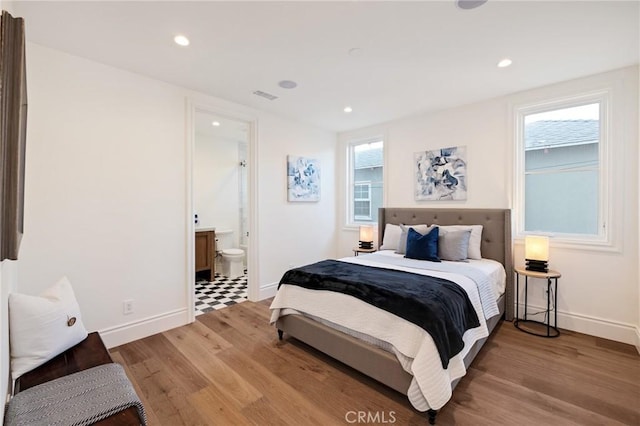 bedroom with connected bathroom and hardwood / wood-style floors