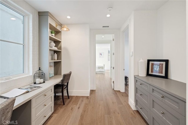 home office featuring built in desk and light hardwood / wood-style floors