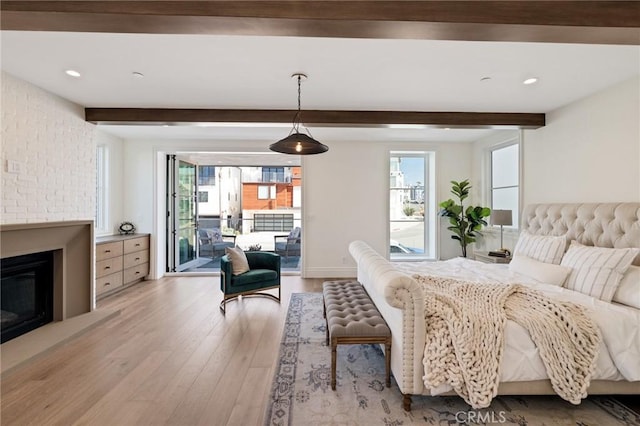 bedroom with access to outside, light hardwood / wood-style floors, and beamed ceiling