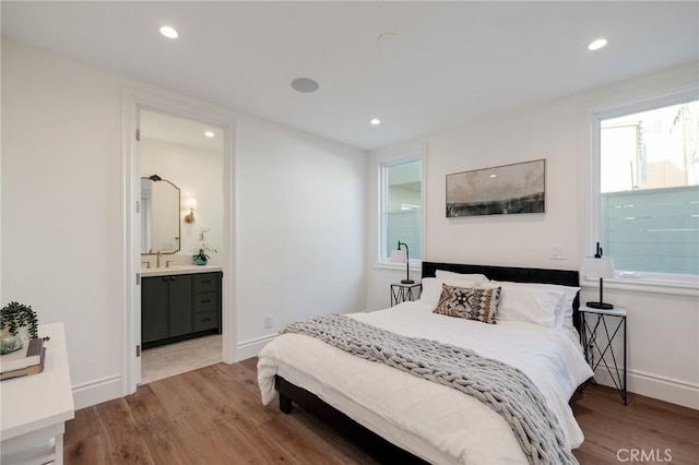 bedroom featuring hardwood / wood-style floors, ensuite bath, and sink