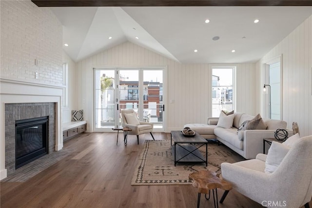 living room featuring plenty of natural light, dark hardwood / wood-style floors, vaulted ceiling, and a brick fireplace