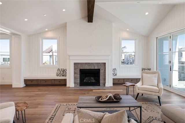 living room featuring a fireplace, light hardwood / wood-style floors, and lofted ceiling with beams