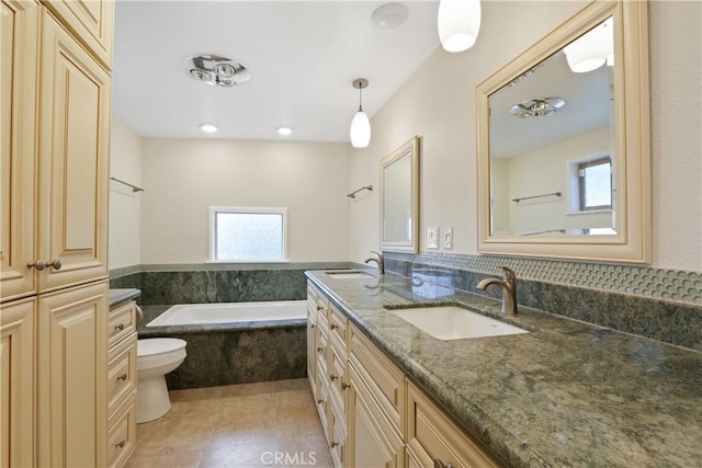 bathroom with tiled tub, tile patterned flooring, vanity, and toilet