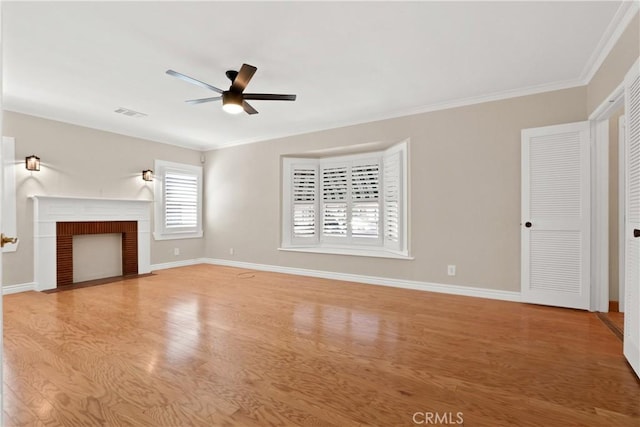 unfurnished living room featuring a brick fireplace, ceiling fan, crown molding, and light hardwood / wood-style flooring