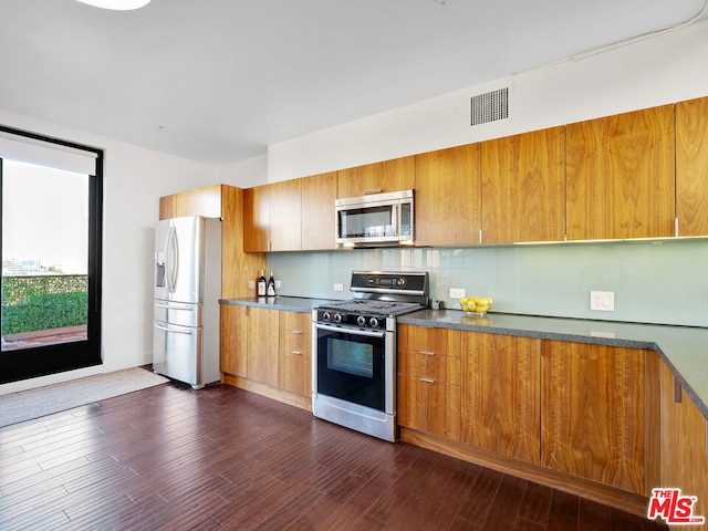 kitchen featuring decorative backsplash, appliances with stainless steel finishes, and dark wood-type flooring