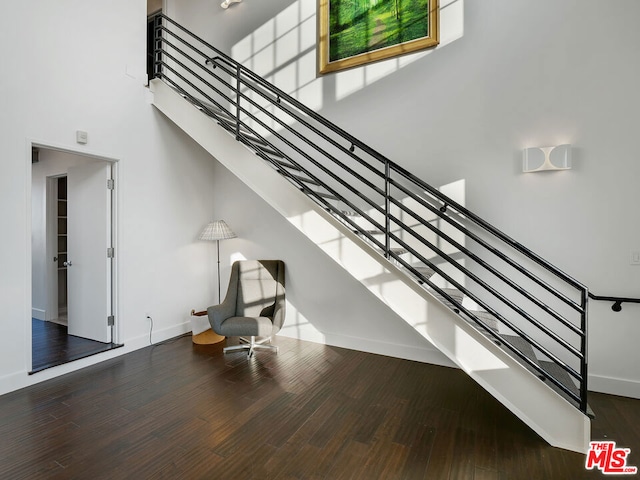 stairway with a towering ceiling and wood-type flooring