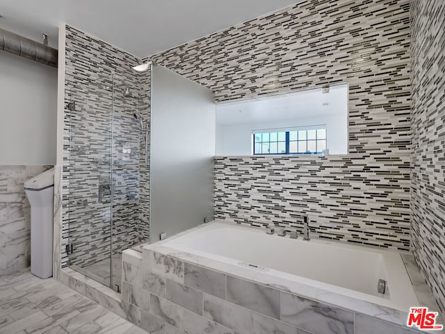 bathroom with shower with separate bathtub and tile walls