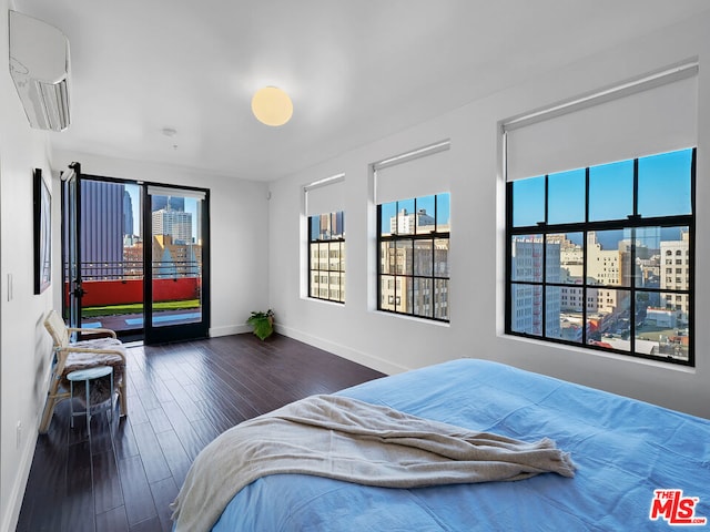 bedroom with a wall unit AC and dark hardwood / wood-style floors