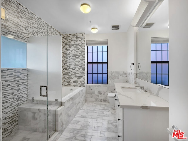 full bathroom featuring vanity, toilet, tile walls, and independent shower and bath