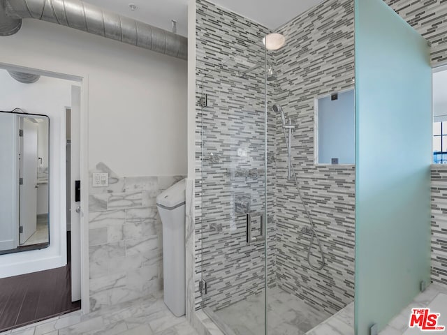 bathroom with a shower with door, tile walls, and hardwood / wood-style flooring