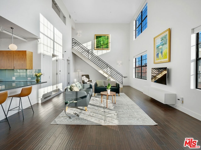 living room featuring a towering ceiling and dark hardwood / wood-style floors