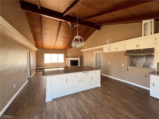 kitchen featuring beamed ceiling, pendant lighting, white cabinetry, and light stone counters