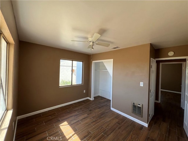 unfurnished bedroom with heating unit, ceiling fan, a closet, and a spacious closet