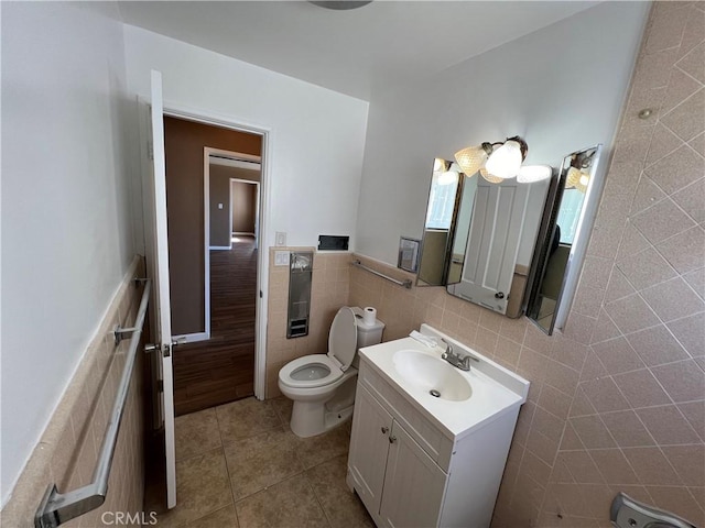 bathroom featuring tile patterned floors, vanity, toilet, and tile walls