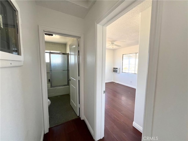 hall featuring a textured ceiling, an AC wall unit, plenty of natural light, and dark wood-type flooring