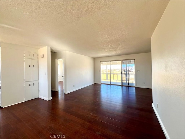 empty room featuring a textured ceiling and dark hardwood / wood-style floors